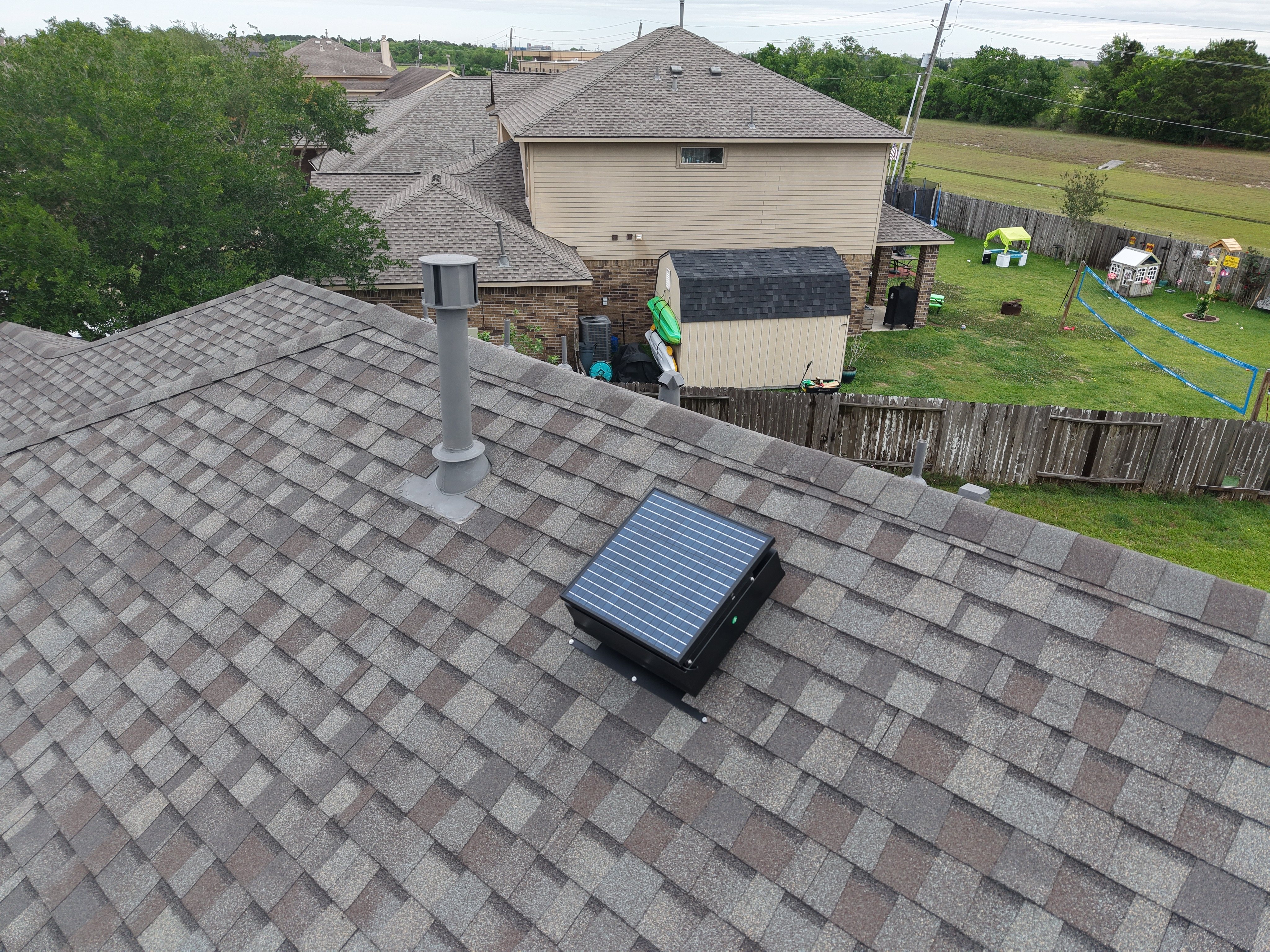 Roofing contractor installing a solar attic fan on a shingle roof