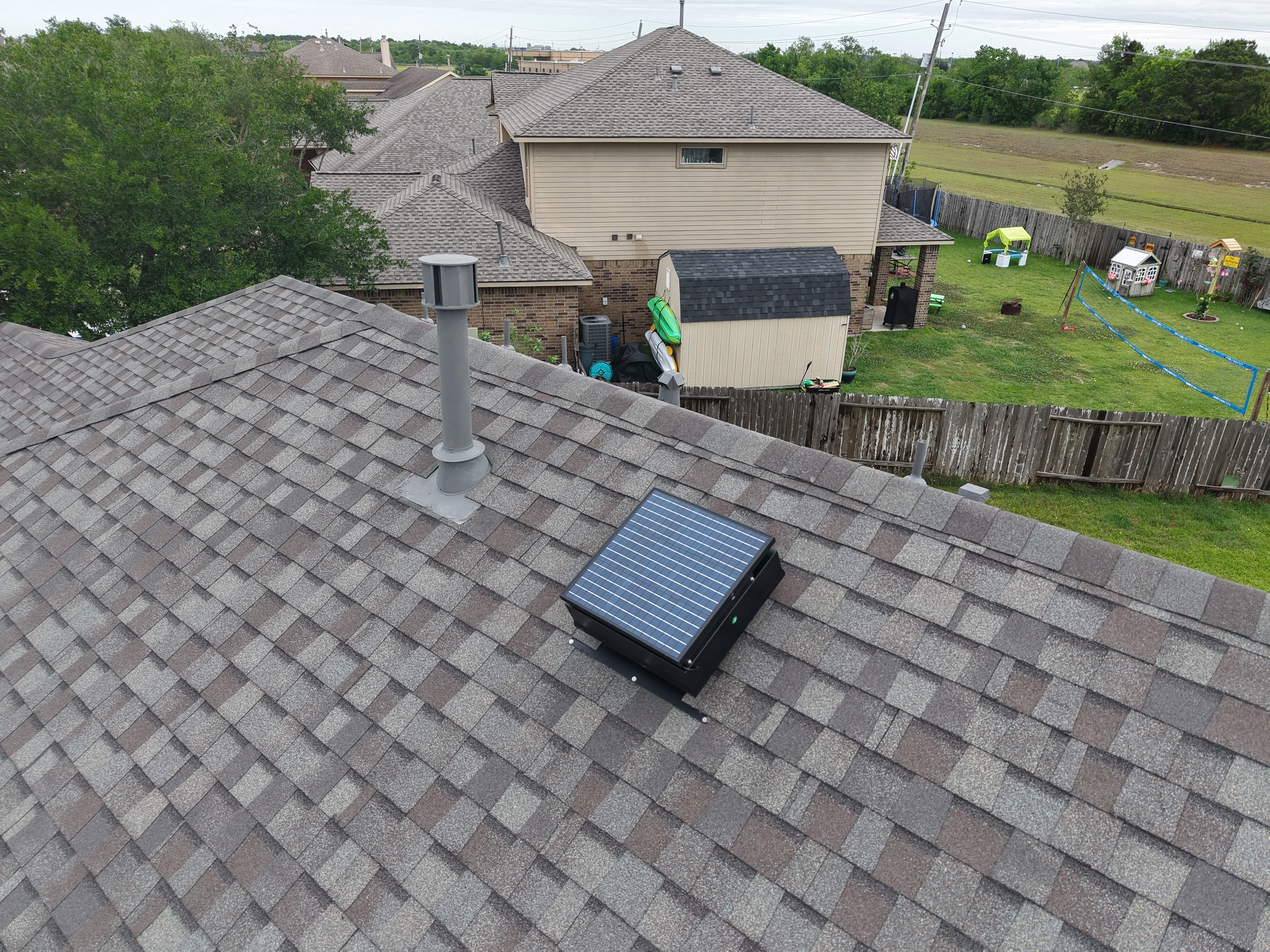 Roofing contractor installing a solar attic fan on a shingle roof