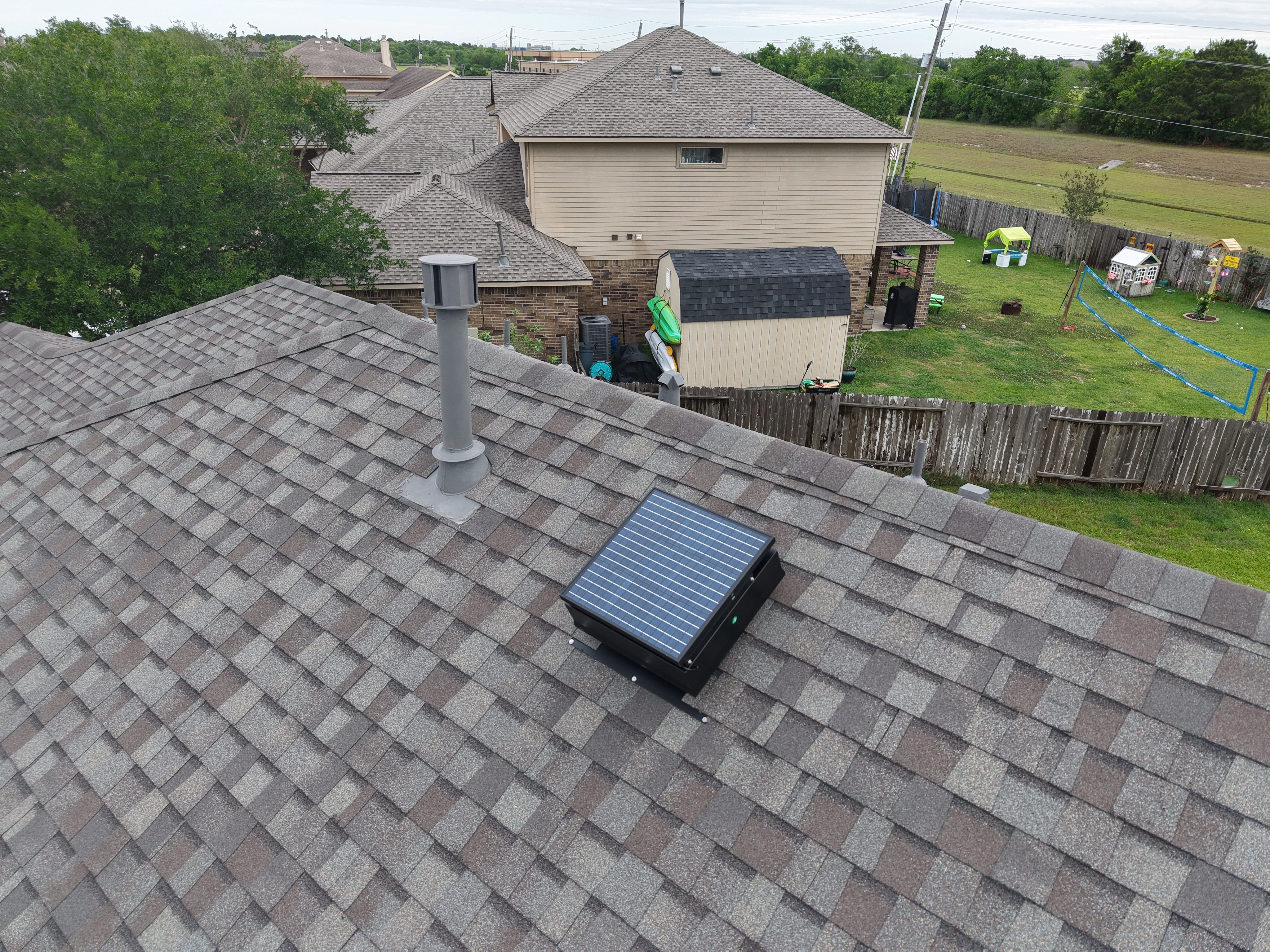 Roofing contractor installing a solar attic fan on a shingle roof